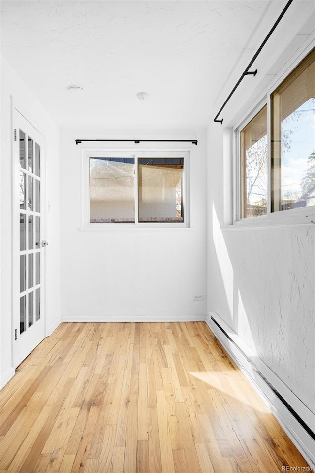 empty room with wood-type flooring and a baseboard radiator