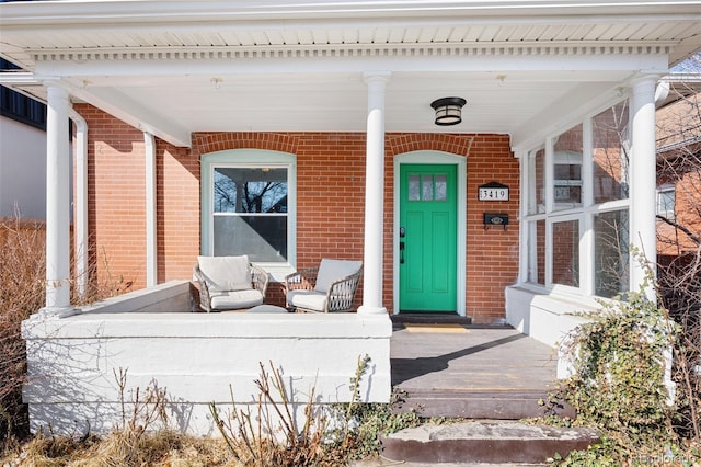 doorway to property with brick siding and a porch