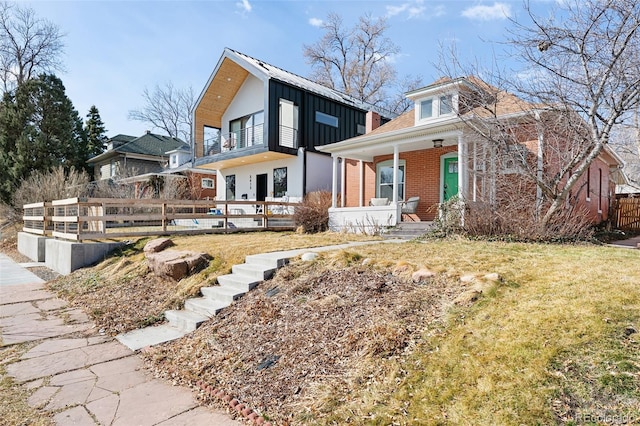 exterior space with brick siding, board and batten siding, fence, a porch, and a balcony