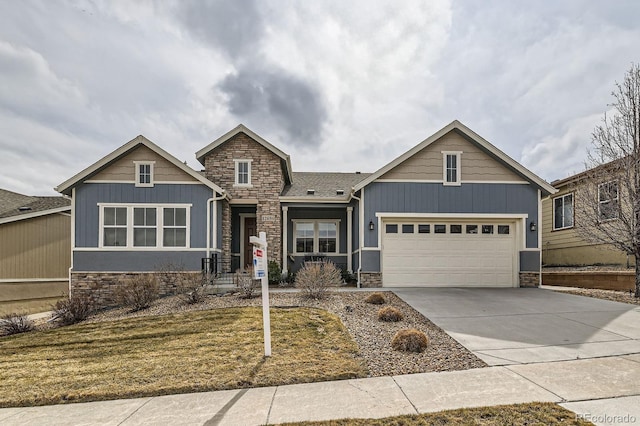 craftsman inspired home with a garage, stone siding, driveway, and board and batten siding