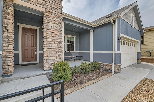 property entrance with a garage, covered porch, stone siding, and roof with shingles