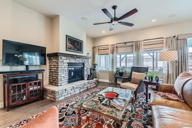 living room with recessed lighting, baseboards, wood finished floors, and a stone fireplace