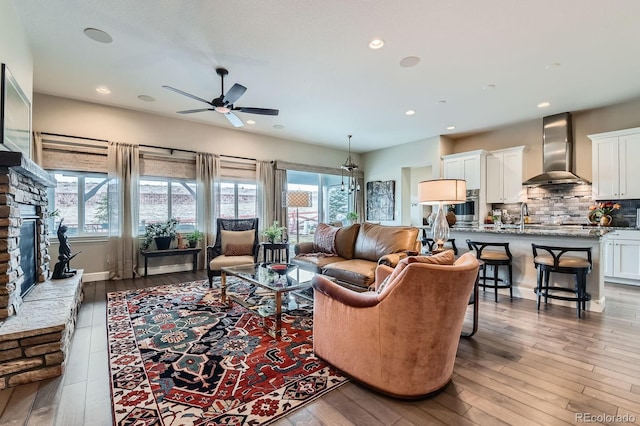 living room with a wealth of natural light, a stone fireplace, and hardwood / wood-style flooring