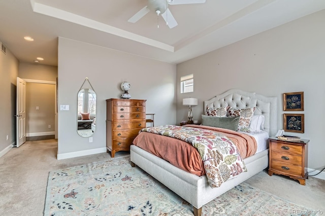 bedroom with light carpet, visible vents, baseboards, a raised ceiling, and ceiling fan