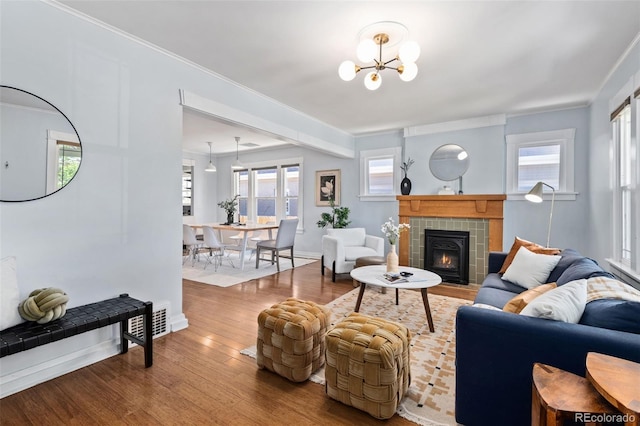 3332 N Vine St, Denver, CO 80205 - living room with wood finished floors, a chandelier, a tiled fireplace, ornamental molding, and baseboards