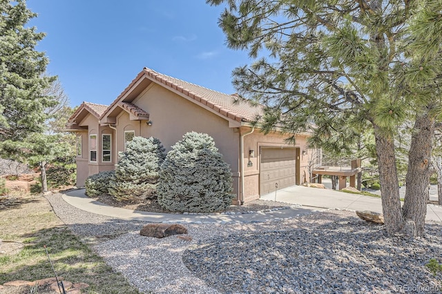 view of home's exterior featuring a garage, a tile roof, concrete driveway, and stucco siding