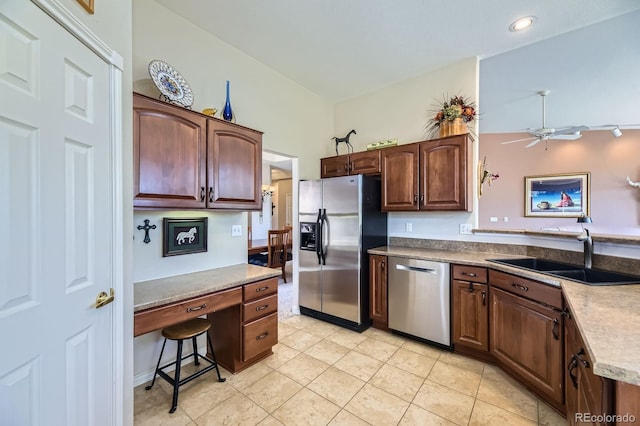 kitchen with a sink, light tile patterned flooring, built in study area, ceiling fan, and appliances with stainless steel finishes