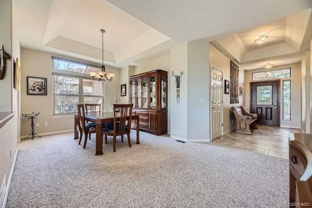 dining area featuring a tray ceiling, carpet floors, plenty of natural light, and an inviting chandelier