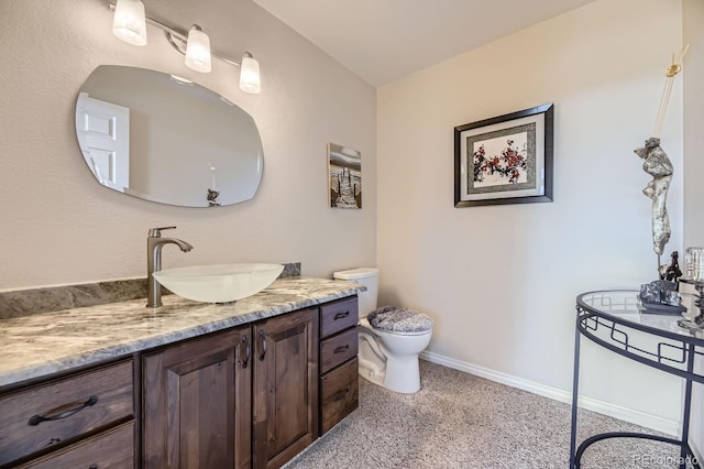 bathroom with toilet, vanity, and baseboards