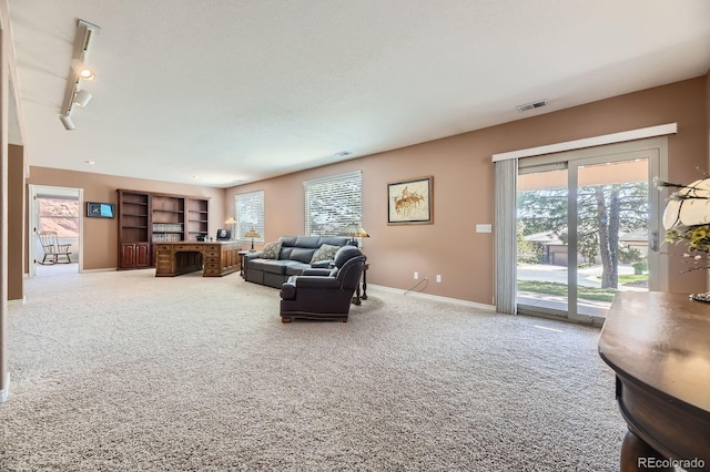 living area featuring baseboards, visible vents, carpet floors, and rail lighting