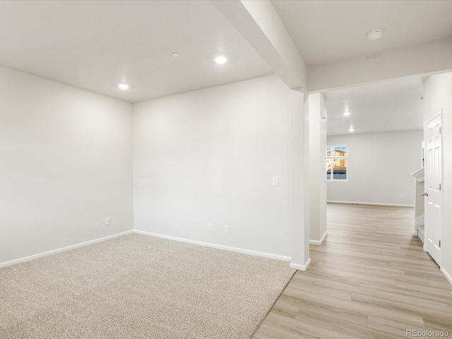 spare room with beam ceiling and light hardwood / wood-style flooring