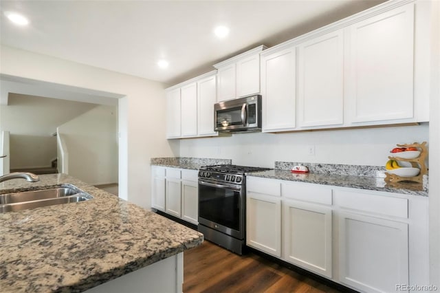 47312 Lilac Ave, Bennett, CO 80102 - kitchen featuring stainless steel appliances, a sink, dark wood finished floors, white cabinetry, and light stone countertops