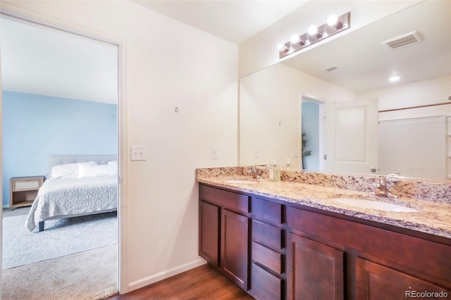47312 Lilac Ave, Bennett, CO 80102 - full bath featuring double vanity, connected bathroom, baseboards, and wood finished floors