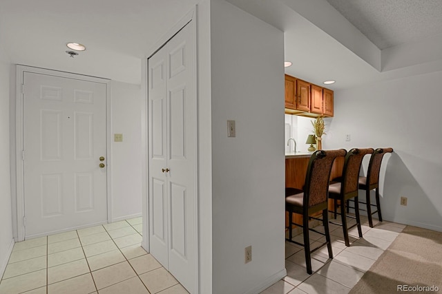 7000 E Quincy Ave Unit 302, Denver, CO 80237 - kitchen with brown cabinets, a breakfast bar area, light tile patterned floors, recessed lighting, and a peninsula