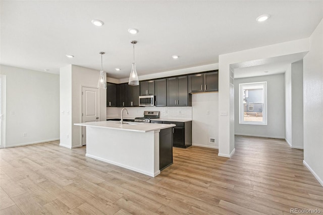 9332 Bahama Ct, Commerce City, CO 80022 - kitchen featuring an island with sink, stainless steel appliances, light wood-type flooring, backsplash, and light countertops