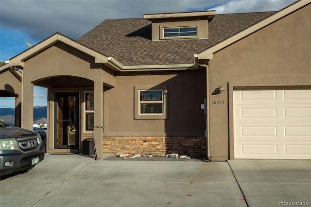 10473 Table Rock Ct Unit E, Poncha Springs, CO 81242 - view of front of home featuring roof with shingles, concrete driveway, stucco siding, and a garage