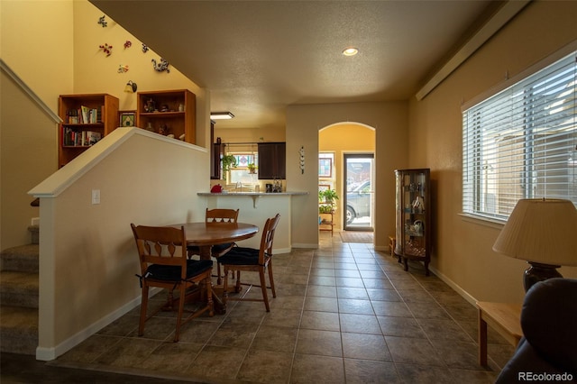 10473 Table Rock Ct Unit E, Poncha Springs, CO 81242 - dining area with arched walkways, a textured ceiling, stairs, baseboards, and dark tile patterned flooring