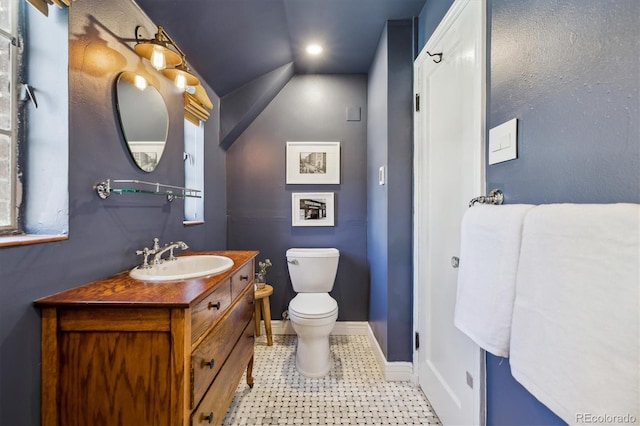 629 Bellaire St, Denver, CO 80220 - half bathroom featuring toilet, baseboards, vanity, and vaulted ceiling