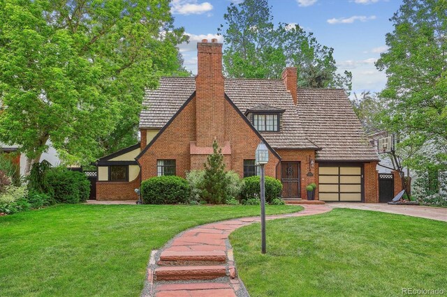 629 Bellaire St, Denver, CO 80220 - tudor house with concrete driveway, brick siding, a front lawn, and a chimney