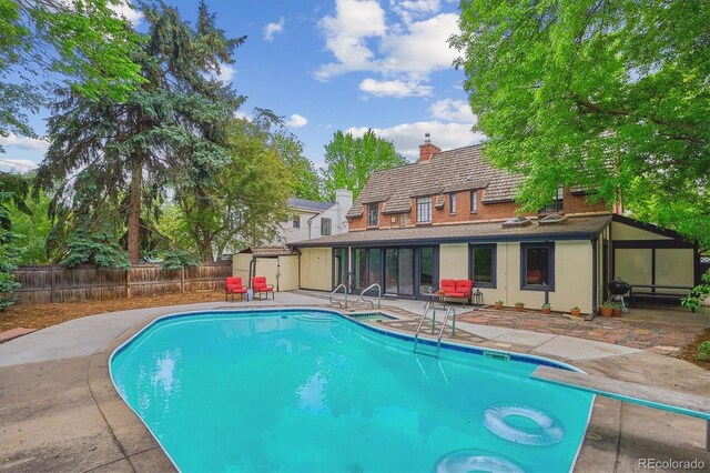 629 Bellaire St, Denver, CO 80220 - view of pool with a patio area, a fenced backyard, a sunroom, and a diving board