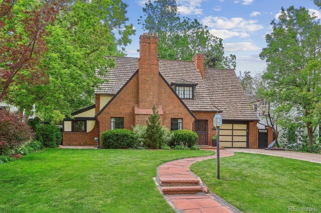 629 Bellaire St, Denver, CO 80220 - english style home featuring concrete driveway, a front yard, a garage, and a chimney
