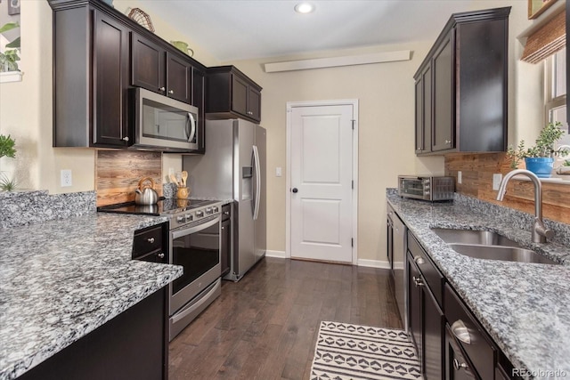 10497 Table Rock Ct, Poncha Springs, CO 81242 - kitchen featuring appliances with stainless steel finishes, light stone counters, tasteful backsplash, dark wood-style flooring, and dark brown cabinets