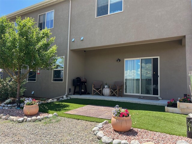 10497 Table Rock Ct, Poncha Springs, CO 81242 - rear view of property featuring a patio, stucco siding, and a yard
