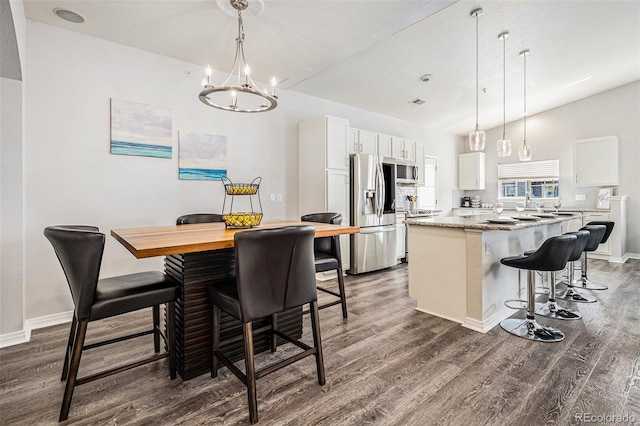 9434 Ashbury Cir Unit 204, Parker, CO 80134 - kitchen featuring appliances with stainless steel finishes, dark wood finished floors, a kitchen island, white cabinets, and a kitchen breakfast bar