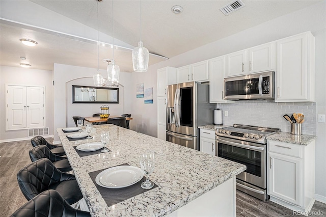 9434 Ashbury Cir Unit 204, Parker, CO 80134 - kitchen with stainless steel appliances, lofted ceiling, dark wood finished floors, white cabinetry, and decorative backsplash