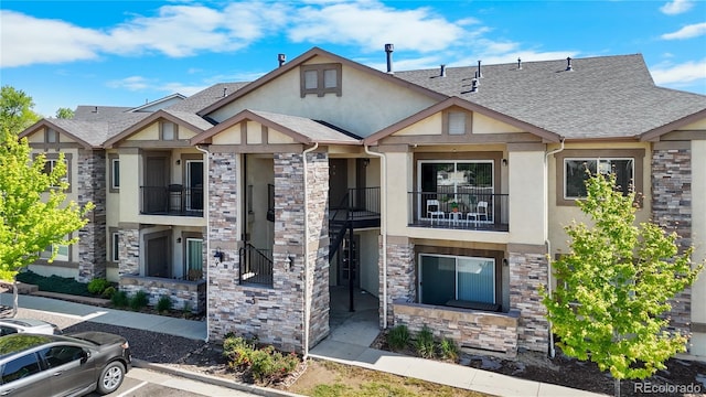 875 E 78th Ave Unit 21, Denver, CO 80229 - view of front of house with stucco siding, a balcony, and stone siding