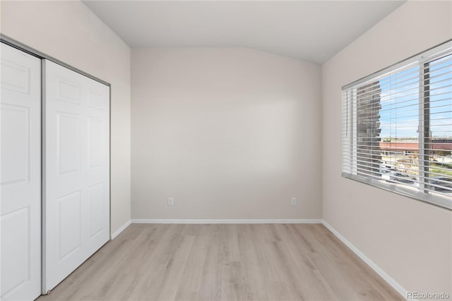 875 E 78th Ave Unit 21, Denver, CO 80229 - unfurnished bedroom with light wood finished floors, multiple windows, a closet, baseboards, and lofted ceiling