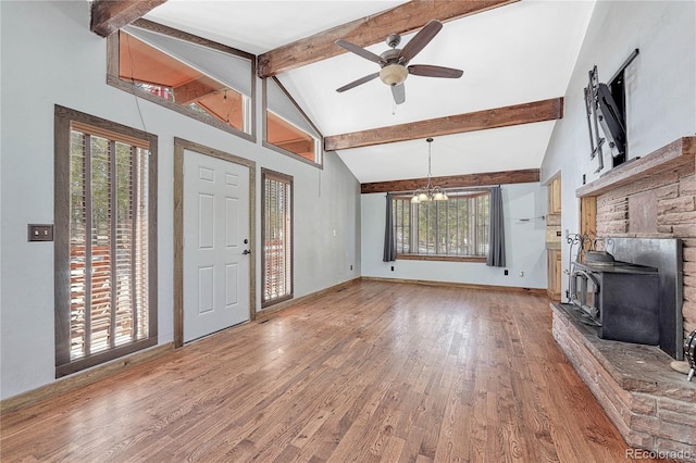 unfurnished living room with beamed ceiling, hardwood / wood-style flooring, a wood stove, high vaulted ceiling, and ceiling fan with notable chandelier