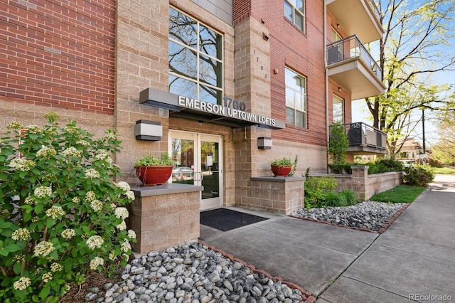 entrance to property with brick siding and a balcony