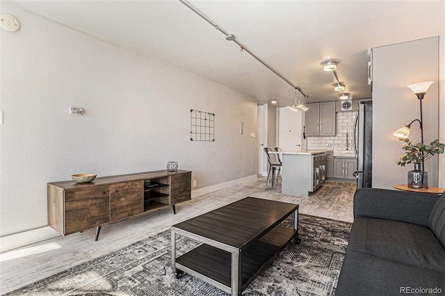 living area featuring baseboards and light wood finished floors