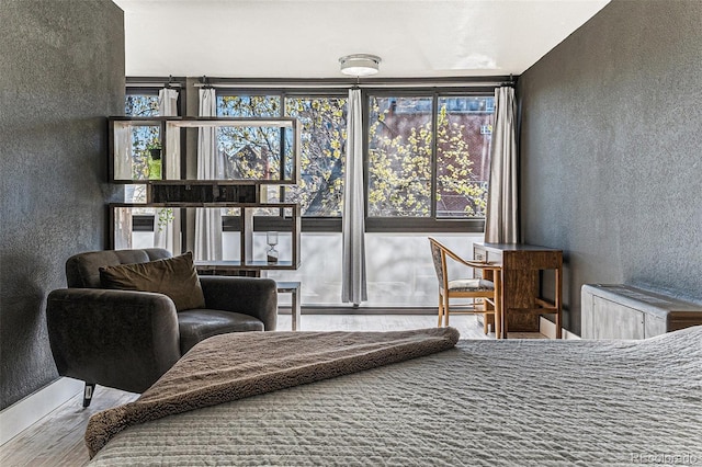 bedroom featuring a baseboard heating unit, a textured wall, and wood finished floors