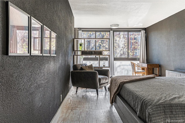 bedroom featuring a textured wall and hardwood / wood-style flooring