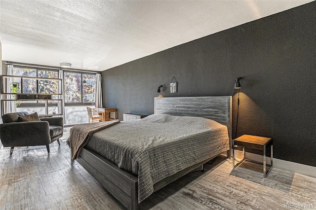 bedroom featuring a textured ceiling, a textured wall, and wood finished floors