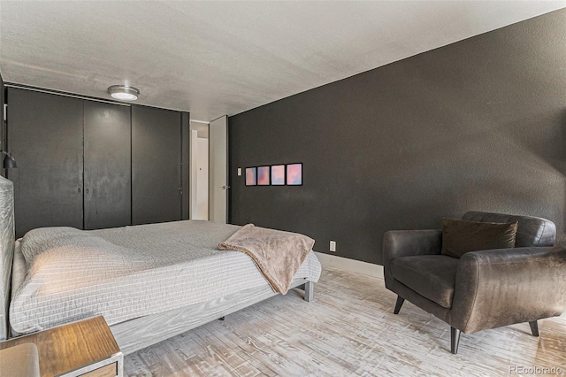 bedroom featuring a closet, light wood finished floors, and baseboards