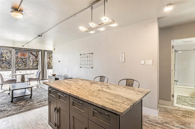 kitchen with baseboards, a textured wall, wood finished floors, and decorative light fixtures