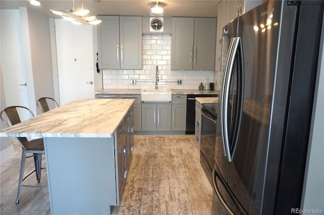 1050 N Corona St Unit 206, Denver, CO 80218 - kitchen with black appliances, a sink, a kitchen bar, and gray cabinetry