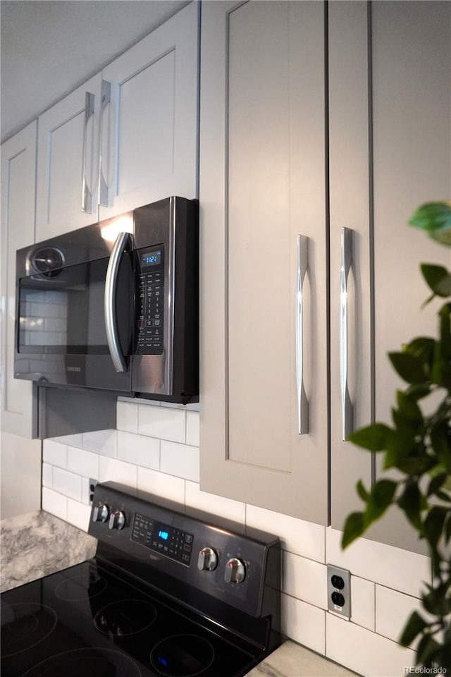 1050 N Corona St Unit 206, Denver, CO 80218 - kitchen view of stainless steel microwave, black range with electric stovetop, backsplash, and light countertops