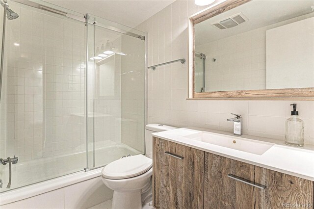1050 N Corona St Unit 206, Denver, CO 80218 - full bath featuring tile walls, toilet, shower / bath combination with glass door, backsplash, and vanity
