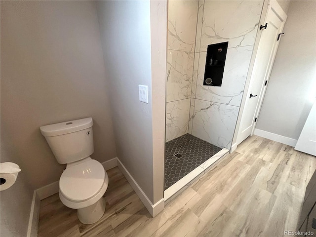 bathroom featuring a tile shower, hardwood / wood-style flooring, and toilet