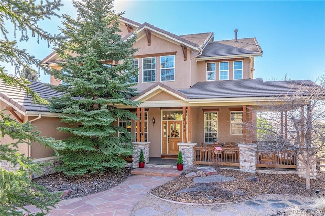 craftsman inspired home with a porch, a tile roof, and stucco siding