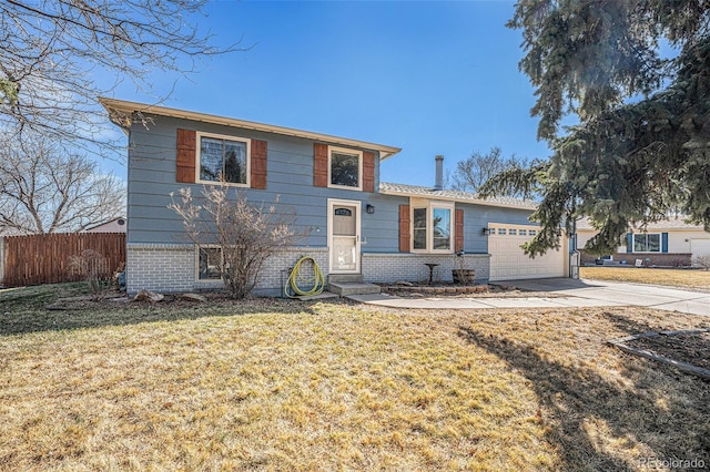 split level home with driveway, fence, a front yard, an attached garage, and brick siding