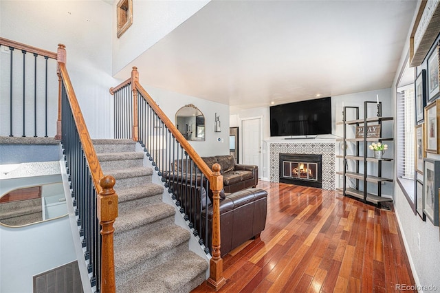 living area featuring a fireplace, stairs, baseboards, and hardwood / wood-style floors