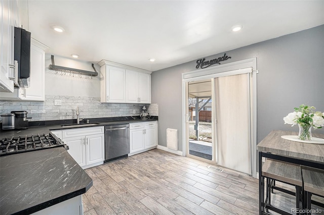 kitchen featuring dark countertops, backsplash, dishwasher, and a sink