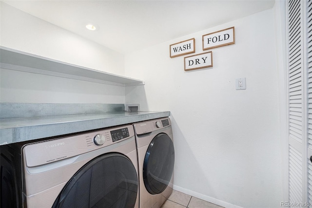 clothes washing area with washer and clothes dryer, laundry area, baseboards, and light tile patterned floors