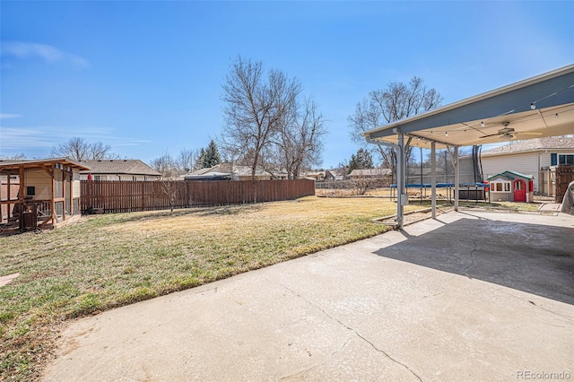 view of yard featuring ceiling fan, a patio, a trampoline, and a fenced backyard