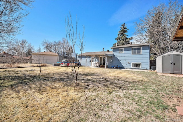 rear view of house featuring a lawn, a trampoline, fence, a shed, and an outdoor structure